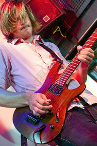 男人吉他手在夜总会的舞台上在一个沉重的独唱表演中星蓝色的图片