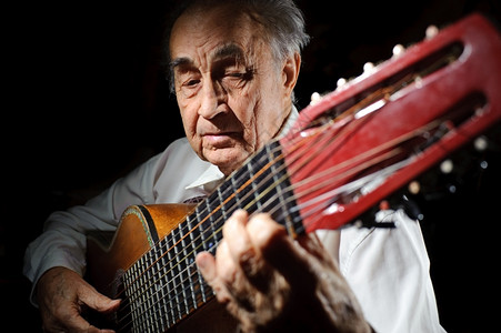 经典的乐器高级一个穿白衬衫老人弹着声音吉他黑暗背景图片
