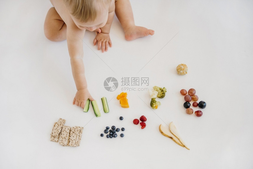 婴儿在多种食物中进行挑选图片