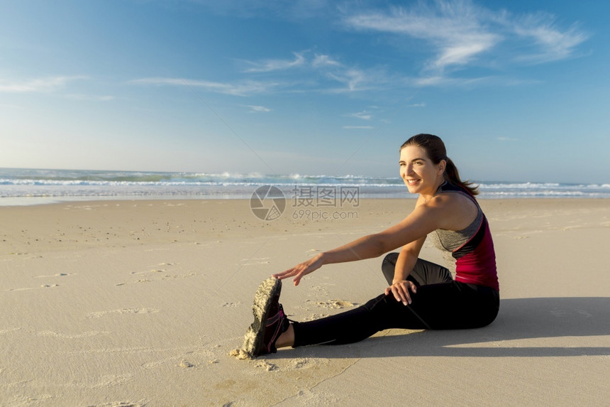 一种拍到个美丽的女人在海滩上做伸展运动的镜头员女图片