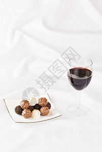 红色的酒和餐桌布上的巧克力盘美味什锦图片