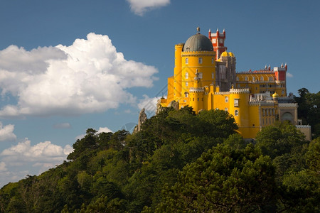 帕拉塔黄色的葡萄牙辛特拉佩纳宫悬崖上森林和云层环绕着辛特拉的葡萄牙Pena宫堡垒塔背景