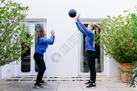 跳两个女青年在露台和药球一起锻炼两个女青年在阳台上教练员苗条的图片
