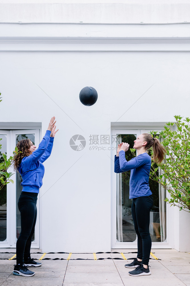 金发女郎健康两个青年在露台和药球一起锻炼两个女青年在阳台上运动衫图片