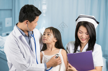疾病快乐的进入亚洲男医生坐在椅子上的亚洲男医生检查小女孩的健康状况护士将数据记录在一张档案中检查小年轻女孩的医生背景图片