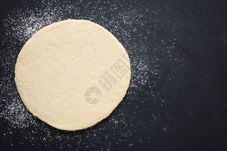 撒粉在面板表铺上披萨团用自然光照在顶部制图片