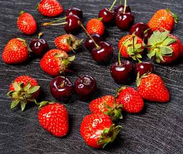盘子黑底的新鲜樱桃和草莓黑底的贝里背景清夏新红莓夹草和樱桃健康混合图片