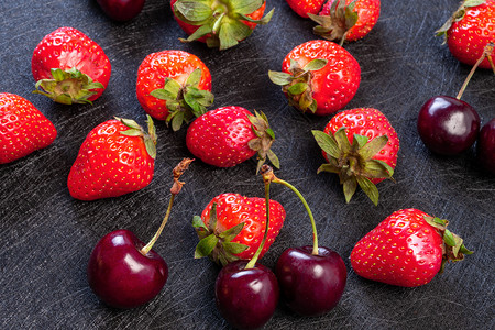甜点黑醋栗底的新鲜樱桃和草莓黑底的贝里背景清夏新红莓夹草和樱桃成熟图片