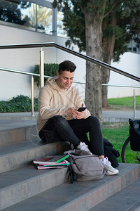 坐在校园楼梯边玩手机的大学生图片