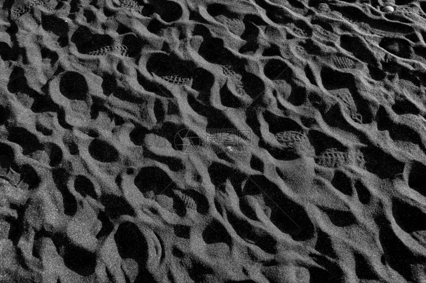晴天自然海滩黑沙上的脚印图片