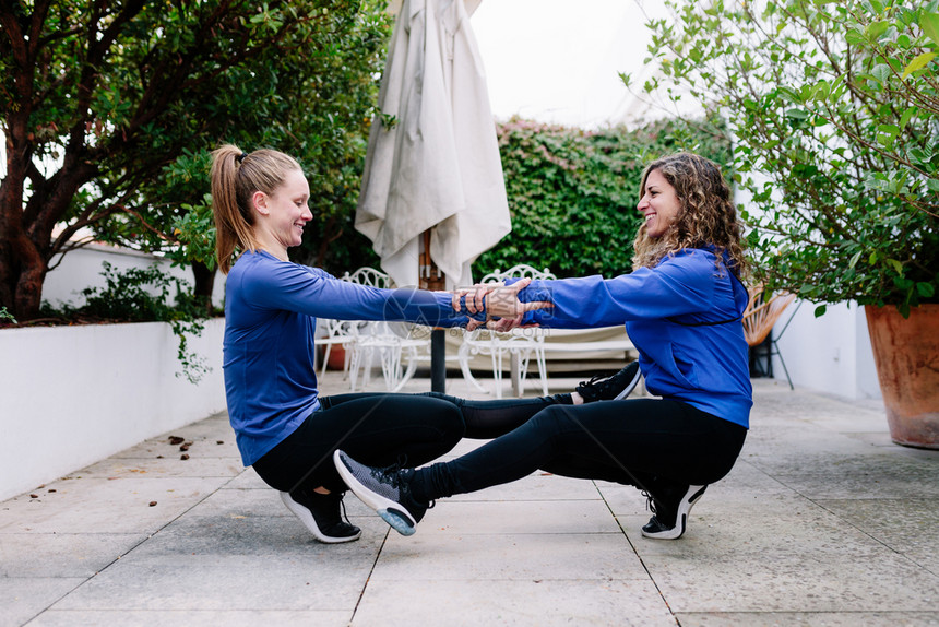 移动外部拉伸两名年轻妇女在露天台一起锻炼图片