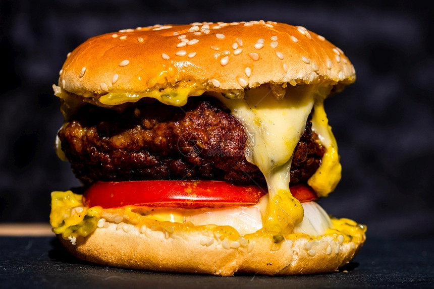 自制黑色背景的新鲜美味牛肉芝士汉堡和熔化乳酪详细数据新鲜的泡菜图片