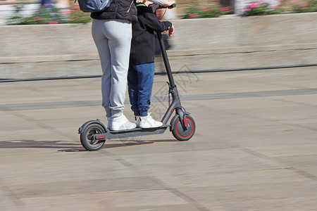 母亲和儿子在市广场乘坐电动脚踏车运模糊电的吸引人运输图片