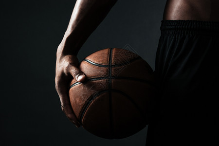 美国黑人裸肌肉男色背景的篮球运动员握着的剪裁照片图片