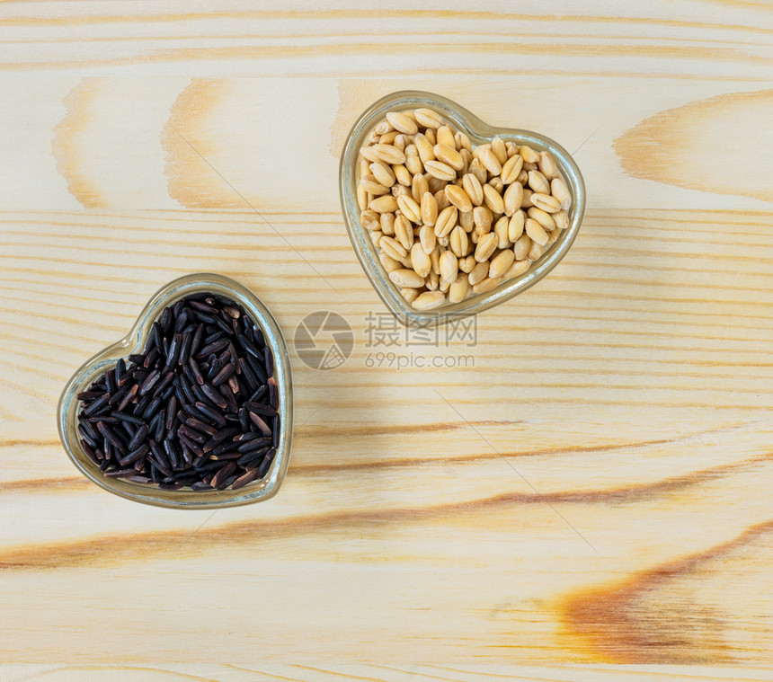 整粒小麦和棕色长稻田大米以玻璃心型碗状的形水缸为稻草木制餐桌顶端风景健康食品概念棕色的黄木制图片