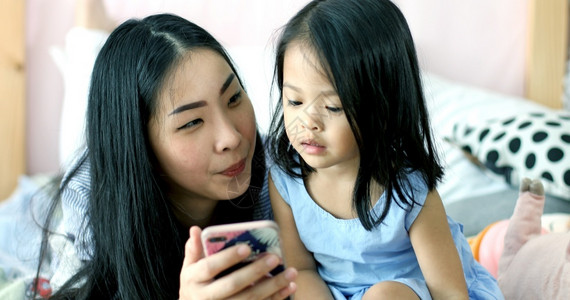 妈妈和孩子趴在一起玩手机图片