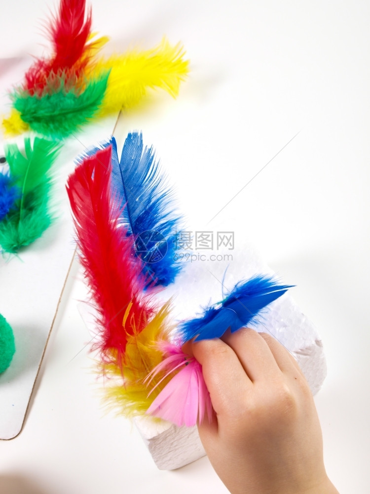 明亮的丰富多彩教育女孩们用双手玩弄多彩羽毛制作复活节装饰品图片