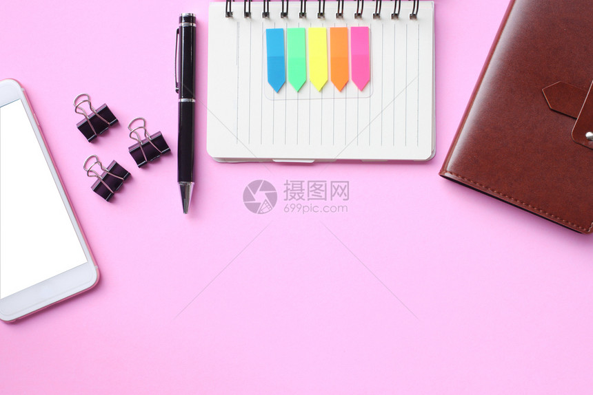 办公室白色的记事本笔和智能手机放在粉红色的地板上在您作品中复制空间图片