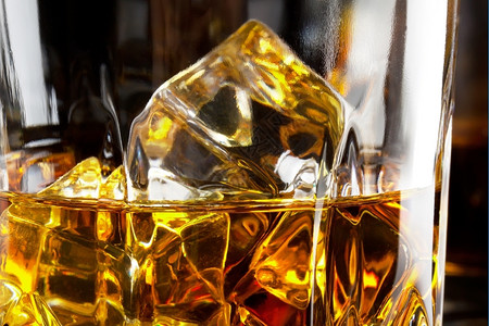 派对一杯威士忌碎片黑底的冰块在棕色的玻璃图片
