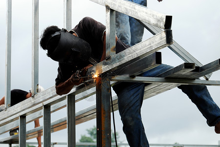 死的在越南胡志明市建造钢房的亚洲男子焊接机攀爬在钢架上和焊接机建设者攀登图片