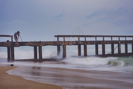 猛攻摄影师海滩三脚架在暴雨当日拍摄海滨码头的照片男子背景