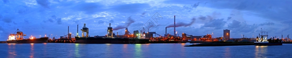 水黄昏时钢铁厂的全景大型船只从铁矿石和煤炭货运中卸下起重机的图片