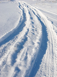 脚印阳光明媚的冬日田野雪轨小路土地图片