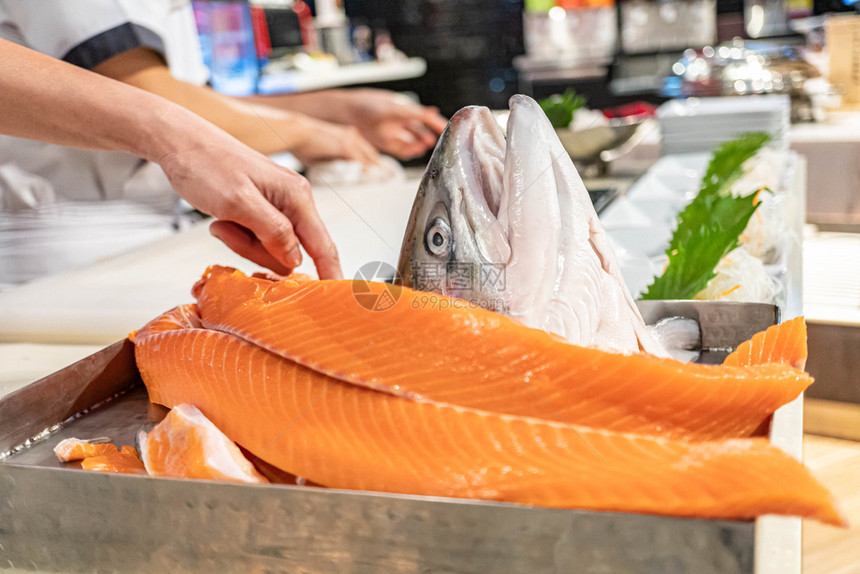 人类厨师在日本餐厅准备和切开新鲜鲑鱼饮食专业的图片