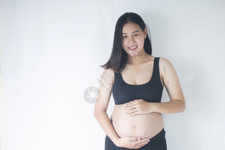 母期待微笑的孕妇站立并抱着她的肚子怀孕图片