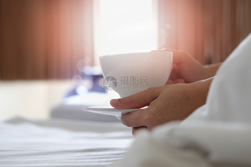 寒冷的老女人早上在床喝咖啡她们杯子图片