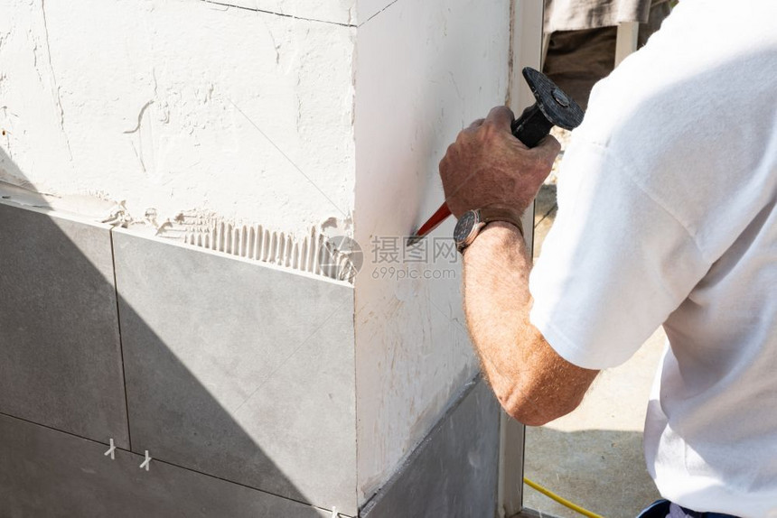 石膏泥瓦匠在铺瓷砖之前用一把砍刀墙壁准备好装修专业的图片