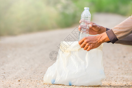 曼诺斯的手正在把塑料瓶捡到垃圾袋里生态概念志愿者采摘自然图片