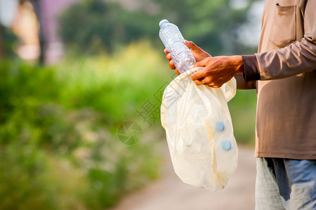 曼诺斯的手正在把塑料瓶捡到垃圾袋里生态概念年轻的污染回收图片