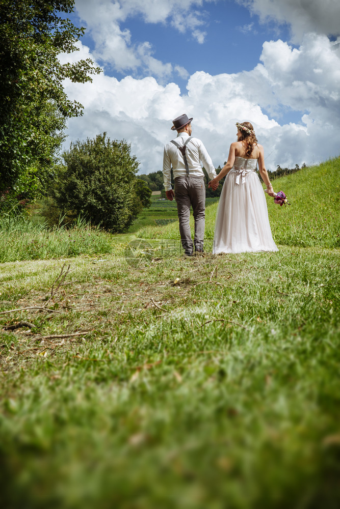 浪漫的照片来自一对年轻新婚夫妇在公园手牵走过一条路年轻的天空图片