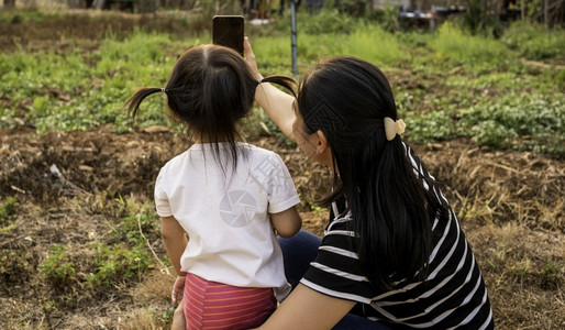父母成人们亚洲小女孩在日落背景下和母亲一起在花园里拍照的背影但图片