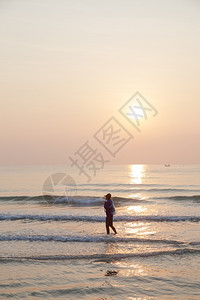 水海岸轮廓人走在滩上早晨太阳升起在海洋之上图片