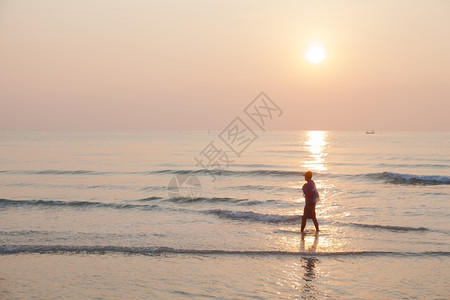 浪漫水人走在海滩上早晨太阳升起在海洋之上年轻的图片
