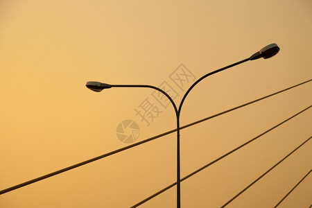 转弯电的力量晚上太阳变橙色时灯杆和绳桥高清图片