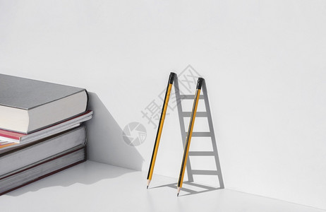 书是人类进步的阶梯泰国木头两支铅笔和双影子以梯形式成在白色桌面上堆叠教科书育学习是成功概念的阶梯乐器背景