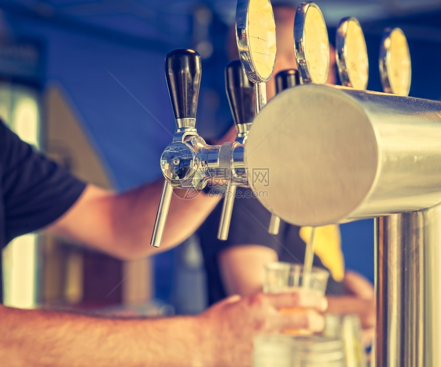 纳达林柜台酒吧的男士手在啤酒龙头上倒着一个灌水啤酒杯在餐馆或里服务看图片