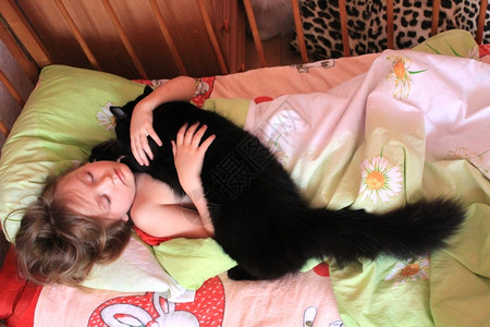 生活小女孩在床上玩猫咪的假期孩子图片