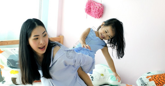 快乐的亚洲小女孩在她母亲的背上在房子里幸福家童年图片