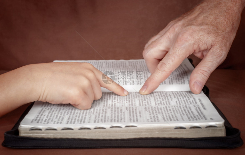 在圣经书中指向一个孩子的人之手教一位来自圣经的门徒学习上帝的言语男生白种人沟通图片