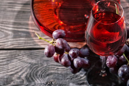 晴天木制背景一杯红酒和串蓝葡萄木制背景一杯红酒和串葡萄小吃酒精图片
