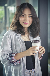 手牵的亚洲女人和热咖啡杯放松情绪微笑着面容观看脸自由职业者背景图片