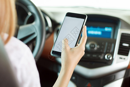 年轻的导航移动亚裔妇女在路上驾驶汽车使用智能手机在路上图片
