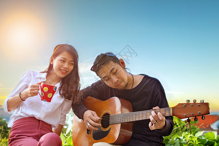 唱歌在公园里弹吉他时放松的情侣和女人在公园里弹吉他咖啡幸福图片