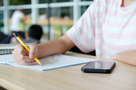青少年写作课女孩手笔记本纸和智能电话放在桌上教育概念图片