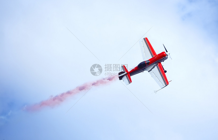红色和白的飞机在天空中排放彩色烟雾运动和自由的概念红色和白的飞机在天空中发射彩色烟雾痕迹抽空气图片