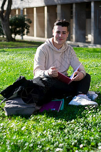 男同学坐在学校草地上看书图片